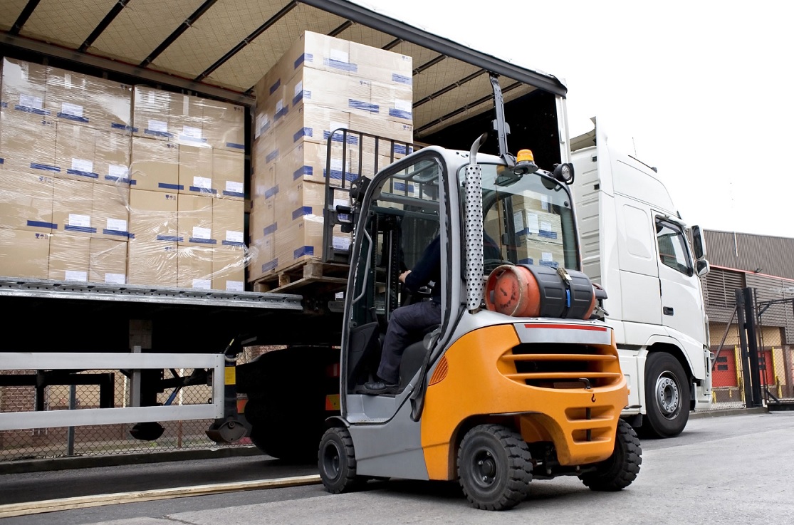 Un montacargas cargando palets de mercancía en un camión para representar el Incoterm FCA (Free Carrier) en logística internacional