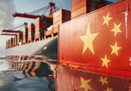 Bandera de china flotando sobre el agua con un buque de carga detrás