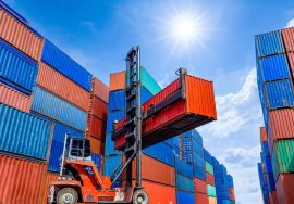 Grúa tipo reach stacker levantando un contenedor en una terminal de carga