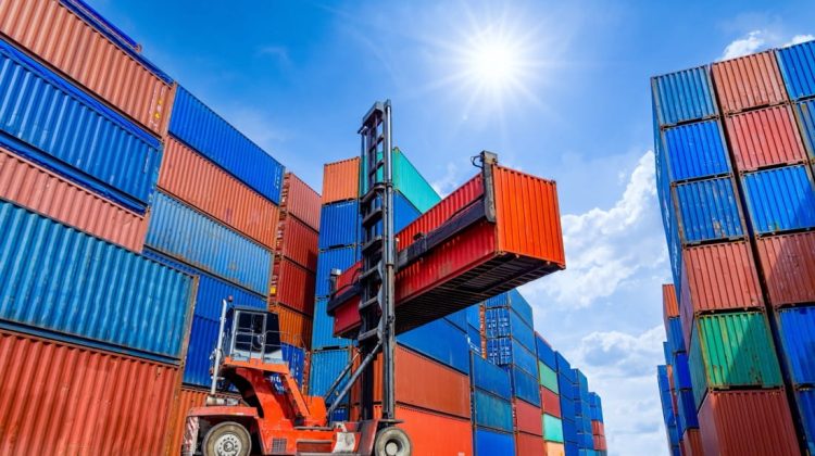 Grúa tipo reach stacker levantando un contenedor en una terminal de carga