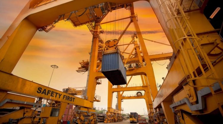 Grúa pórtico levantando un contenedor en una terminal portuaria de carga