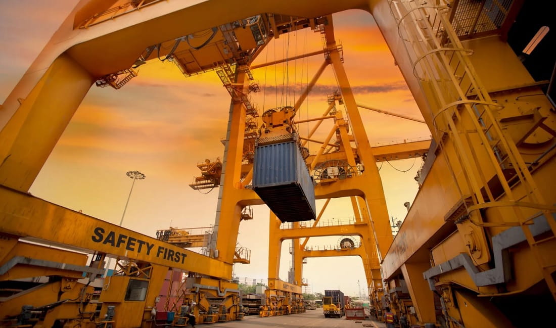 Grúa pórtico levantando un contenedor en una terminal portuaria de carga