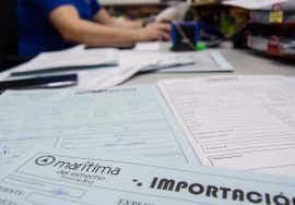 Profesional trabajando en computadora con documentos aduaneros a la vista