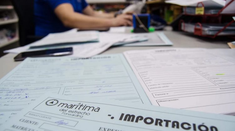 Profesional trabajando en computadora con documentos aduaneros a la vista