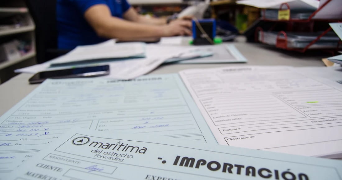 Profesional trabajando en computadora con documentos aduaneros a la vista