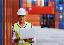 Operador logístico sosteniendo notebook en depósito de contenedores