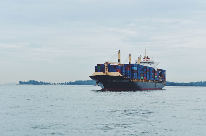 Container ship with colorful stacked cargo containers on a calm sea surface